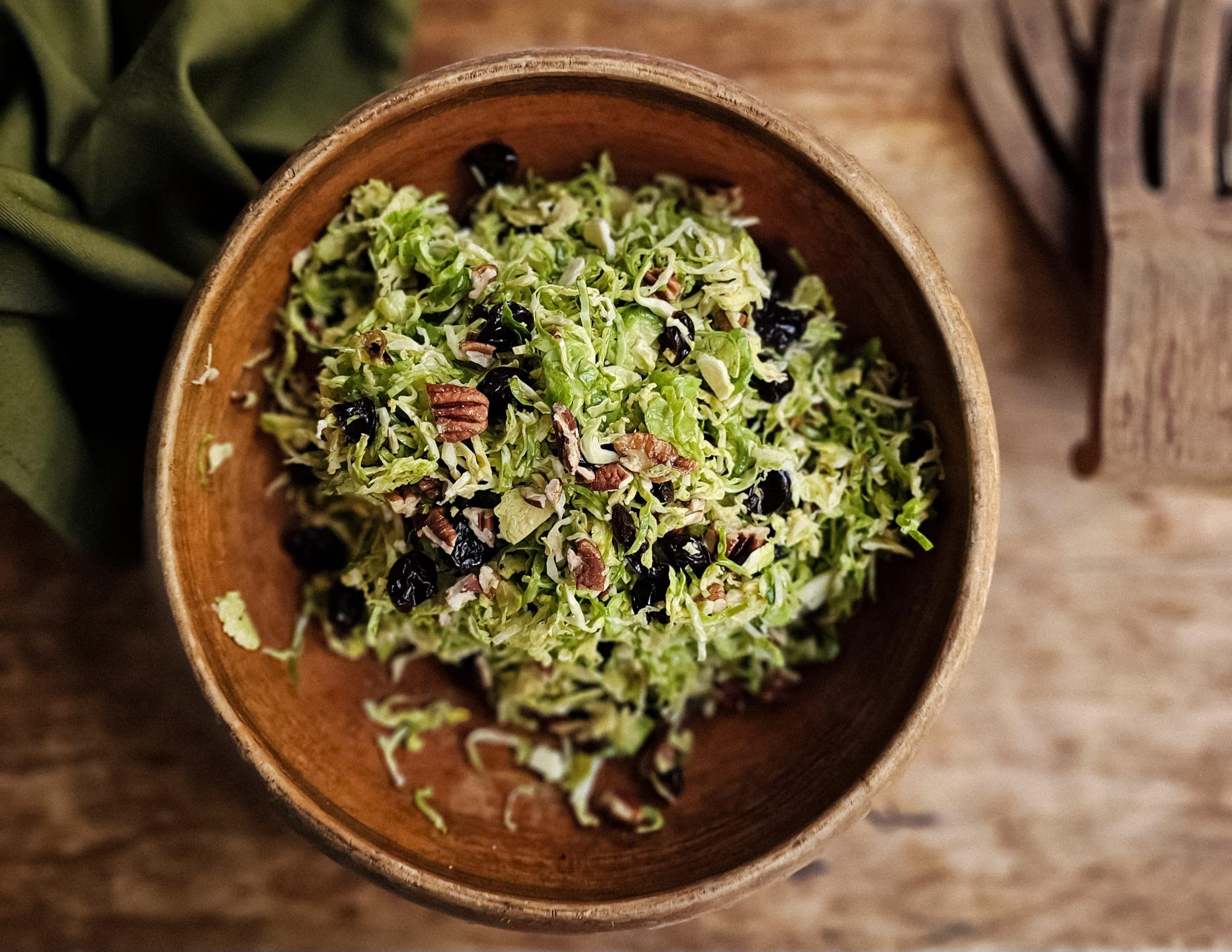 Shaved Brussel Sprout Salad with Toasted Pecans and Cranberries in brown bowl