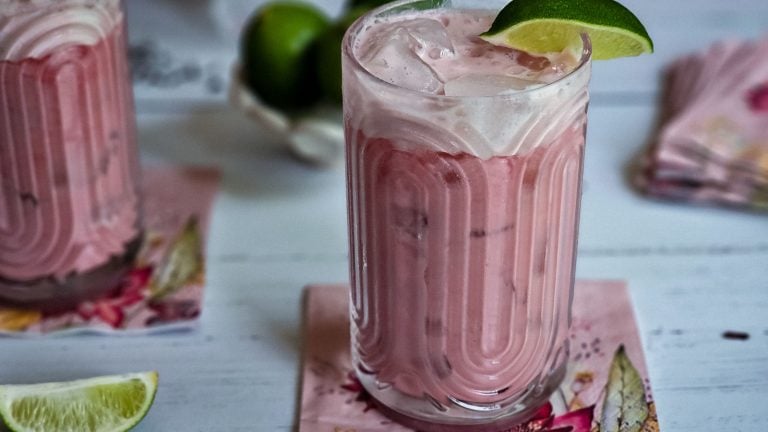 glass of hibiscus lemonade with lime wedge garnish